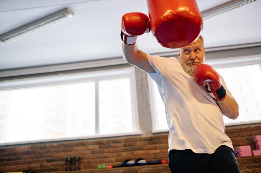 man hitting heavy bag with boxing gloves
